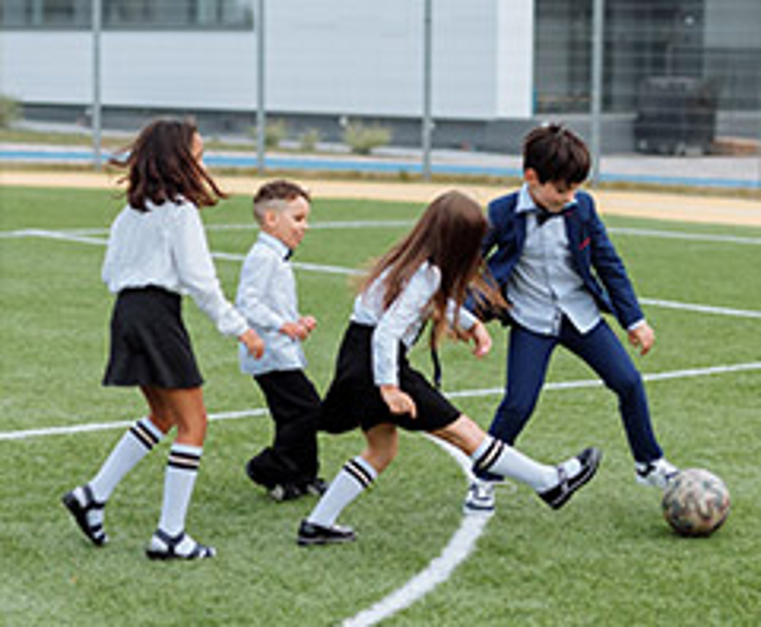 dzieci grające w piłkę nożną na orliku