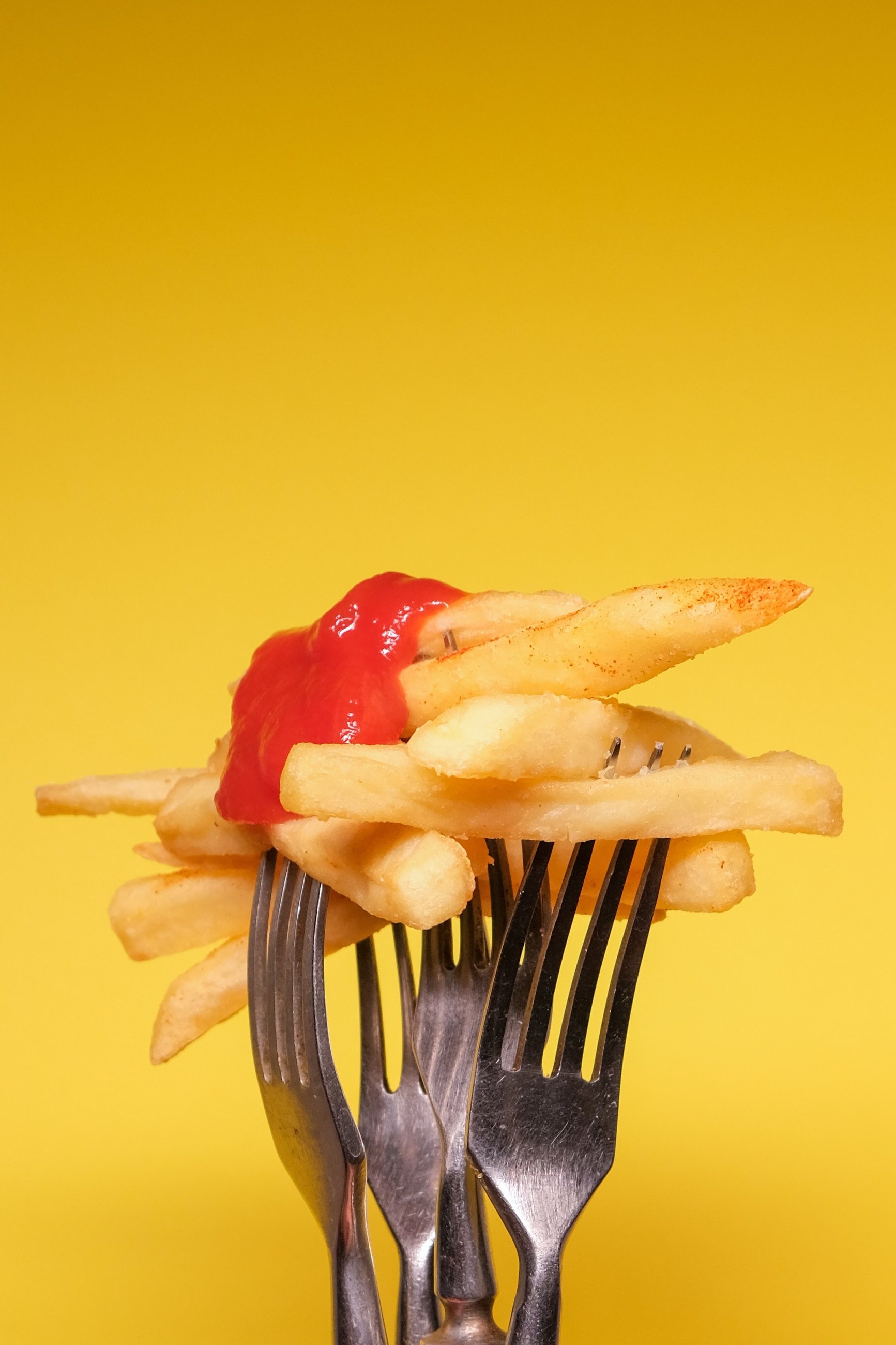 kaloryczny posiłek, frytki z ketchupem na widelcu
