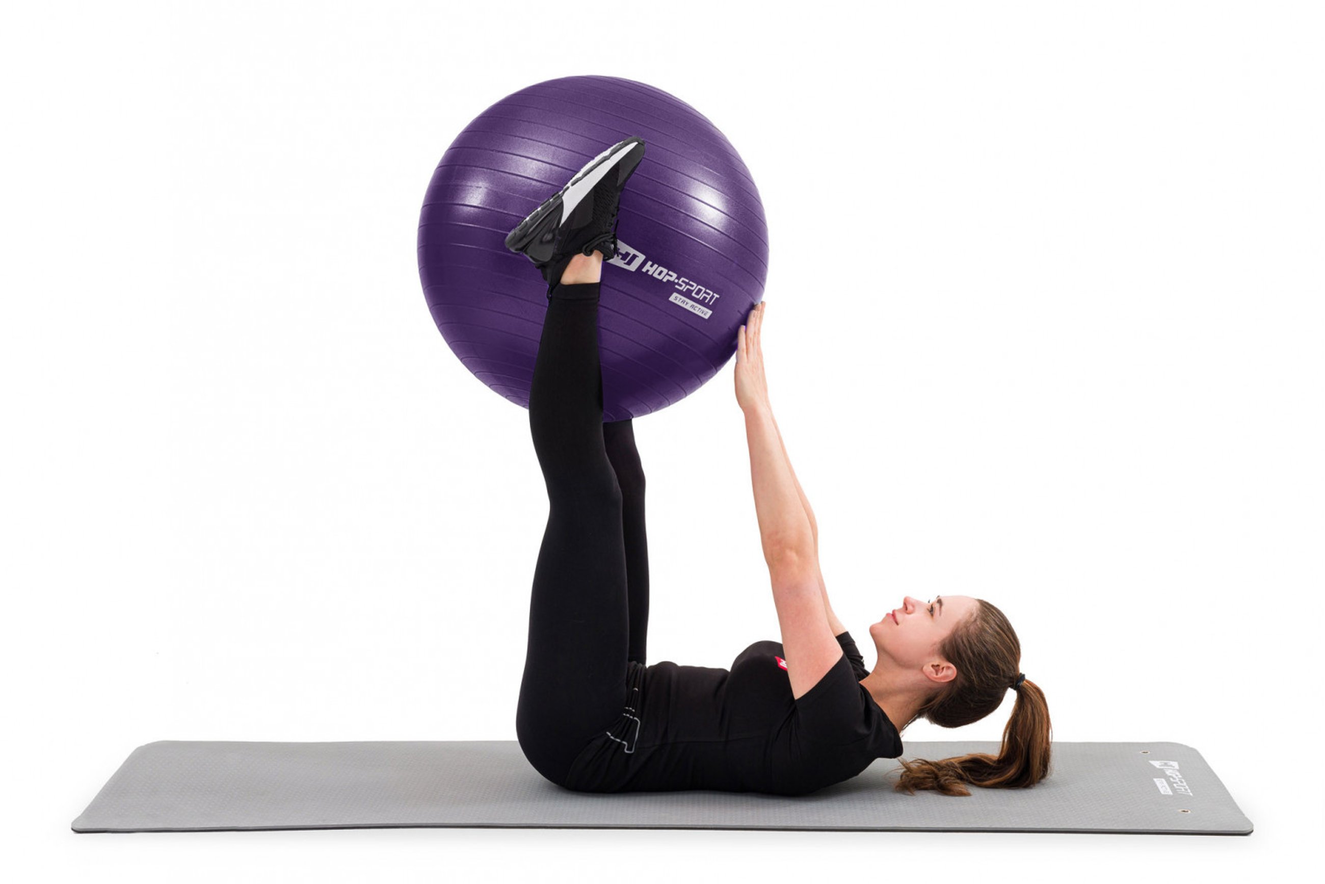 modelka ćwicząca na szarej macie fitness z fioletową piłką gimnastyczną marki Hop-Sport