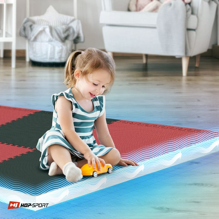 Dziecko siedzące na czarno-czerwonej macie puzzle Hop-Sport