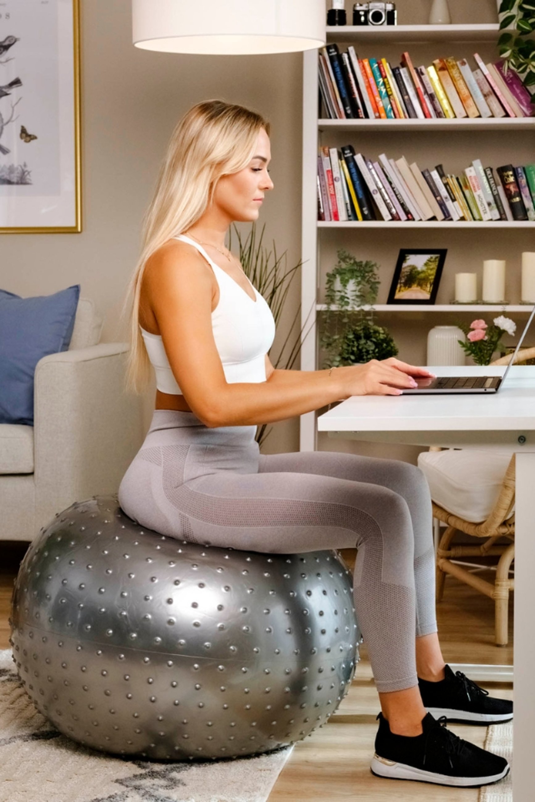 kobieta siedząca przy biurku na piłce gimnastycznej z wypustkami marki Hop-Sport