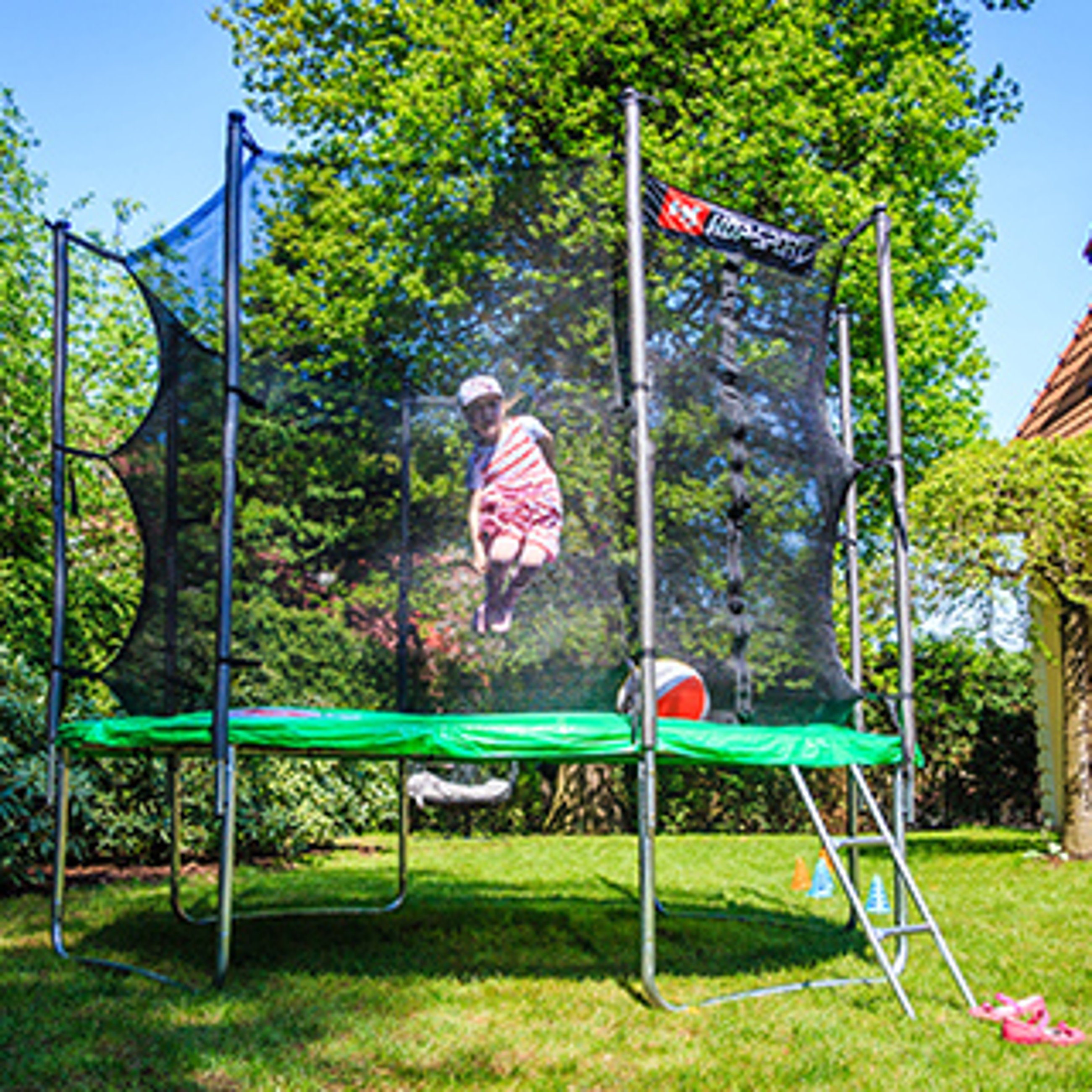 dziewczynka skacząca w trampolinie ogrodowej z siatką wewnętrzną marki Hop-Sport