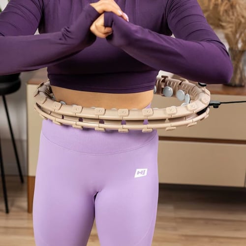 Kobieta podczas treningu z hula hop z wypustkami – przyrząd założony na talii, gotowy do ćwiczeń modelujących brzuch. Regularne używanie hula hop z wypustkami daje widoczne efekty w obszarze talii i bioder.