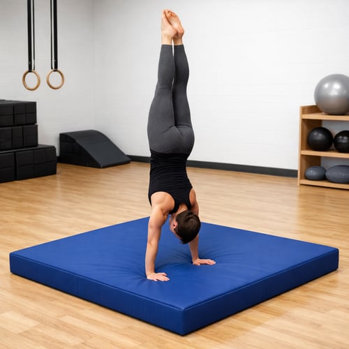 Trenująca kobieta wykonująca stanie na rękach na grubym materacu gimnastycznym w sali fitness – jaki materac gimnastyczny sprawdzi się do akrobatyki i gimnastyki sportowej.