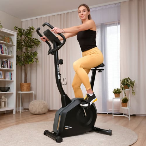 Kobieta trenująca na rowerze stacjonarnym HS-4000H Grant marki Hop-Sport w domu — alternatywa dla osób szukających informacji jakie urządzenie wybrać do ćwiczeń w warunkach domowych.