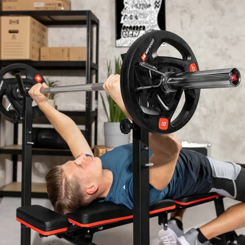 Mężczyzna wykonujący wyciskanie na ławce z obciążonym gryfem olimpijskim – praktyczny przykład różnic w treningu gryf olimpijski a zwykły.