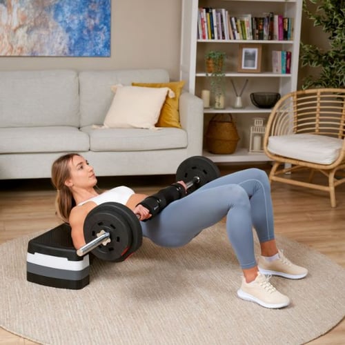 kobieta wykonująca hip thrust ze sztangą w salonie