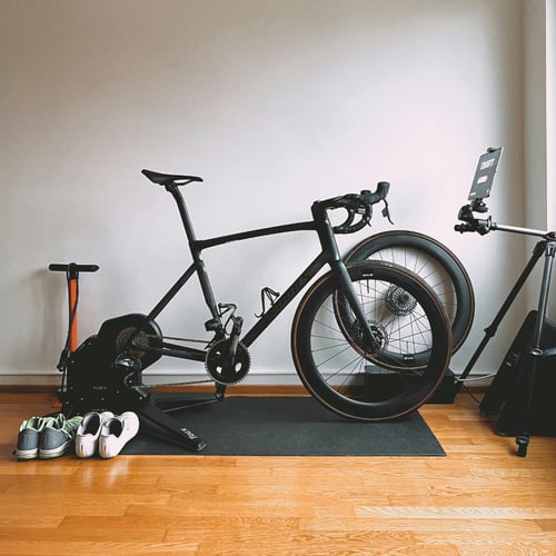 Rower szosowy zamocowany na trenażerze w domowym studio treningowym — idealne rozwiązanie dla osób szukających odpowiedzi, czym jest trenażer i jak działa w warunkach domowych.