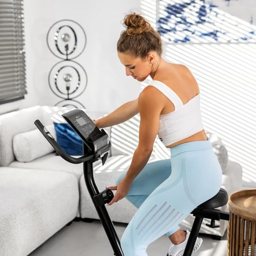 kobieta regulująca pokrętło oporu w rowerze stacjonarnym HS-2070 Onyx marki Hop-Sport