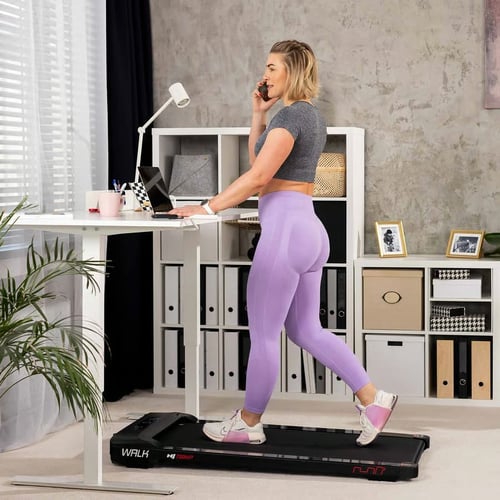 Kobieta prowadząca rozmowę telefoniczną i jednocześnie chodząca na bieżni pod biurkiem – funkcjonalna bieżnia pod biurko ranking.