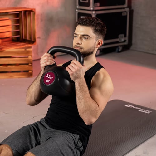 mężczyzna wykonujący brzuszki z kettlebell 14 kg marki Hop-Sport