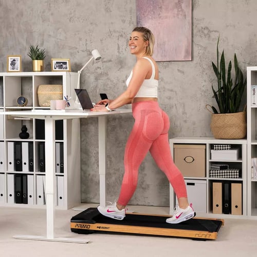 Kobieta pracująca przy komputerze na stojąco, chodząca na bieżni pod biurkiem w nowoczesnym domowym biurze – bieżnia pod biurko ranking.