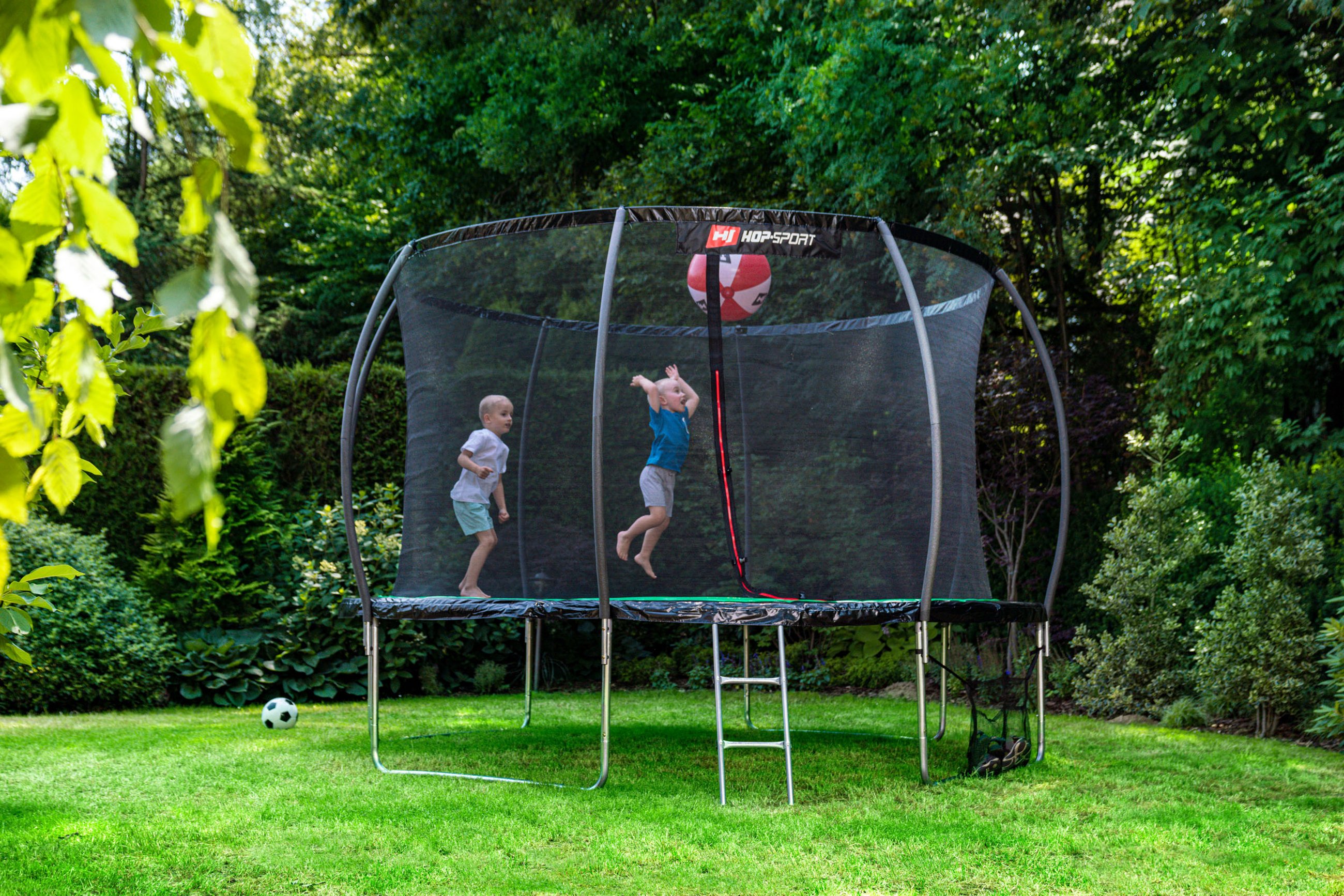 dzieci skaczące na trampolinie ogrodowej Hop-Sport w ogrodzie