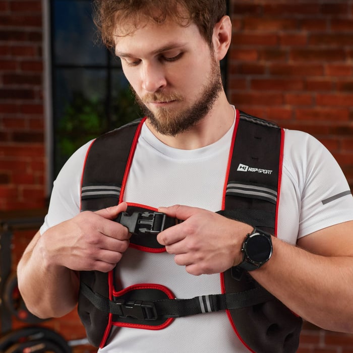 Detail shot of the secure chest strap and buckle system of a Hop-Sport weighted vest worn over a white t-shirt.