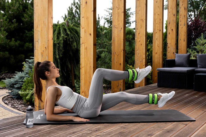 kobieta ćwiczy mięśnie brzucha z zielonymi obciążnikami marki Hop-Sport
