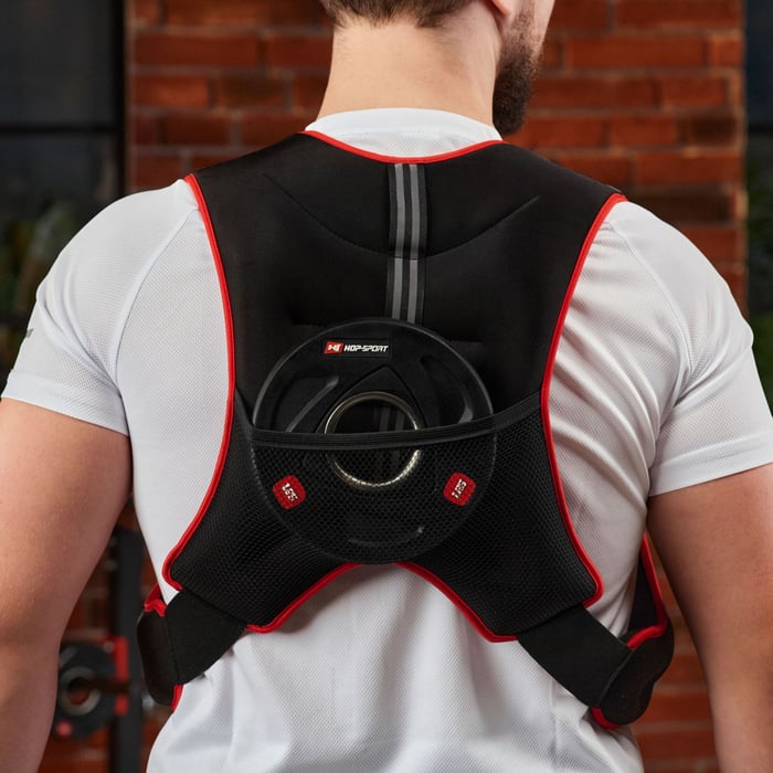 Close-up showing the back pocket of a black weighted vest holding a weight plate for adjustable resistance.